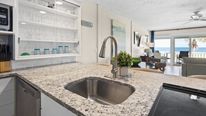 A modern kitchen with a granite countertop, stainless steel sink, and a built-in wine rack. - 621 Surf Villas, Oceanfront Condo, BAM Vacation Rentals (Ponte Vedra Beach)