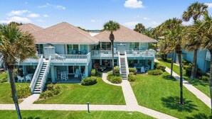 A two-story building with a balcony on the second floor, surrounded by well-maintained lawns and palm trees. - 621 Surf Villas, Oceanfront Condo, BAM Vacation Rentals (Ponte Vedra Beach)
