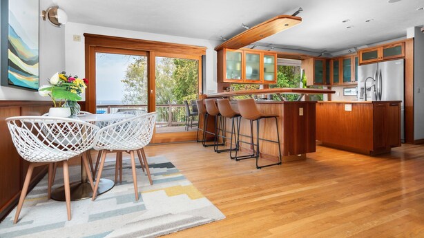 A modern kitchen with wooden cabinets, a central island, and bar stools. - Incredible Mid-Century Modern Waterfront Home on West Bay, on M22 - Sleeps 12 (Suttons Bay)