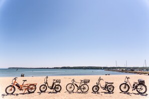 A beach with bicycles lined up on the sand.
