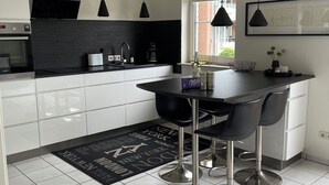 Een moderne keuken met een zwart aanrecht, roestvrijstalen apparatuur en hanglampen.
