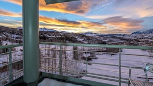 Un balcón con vistas a un paisaje nevado y montañas al atardecer.