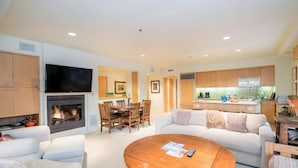 Una sala de estar moderna con chimenea, televisor de pantalla plana, comedor y cocina.