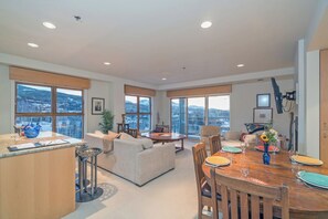 Un amplio salón con una mesa de comedor, sofás y ventanas grandes que ofrecen vistas a la ciudad.