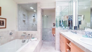 Un baño moderno con una bañera grande, zona de ducha separada y tocador con espejo.