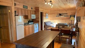 Interior de una cabaña de madera con cocina, comedor y zona de estar.