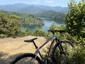 A mountain bike parked on a dirt path with a view of a lake and mountains in the background. - Beautiful North Carolina Mountain View Cabin  near White water rafting NOC (Bryson City)