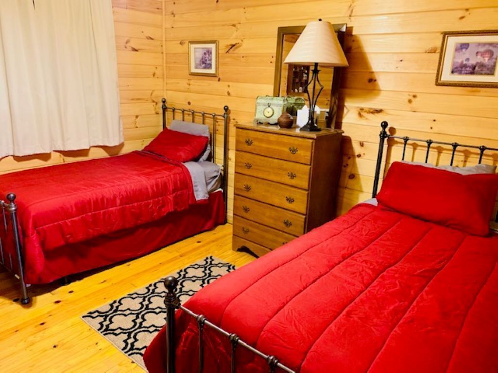 Een houten kamer met twee bedden, een kapstok, een lamp en een spiegel.