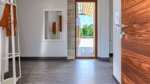 A modern interior with a stone accent wall, a wooden door, and a view through a glass door to an outdoor area.