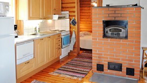 Kompakti keittiö, jossa on puiset kaapit, valkoinen liesi ja tiiliuuni.