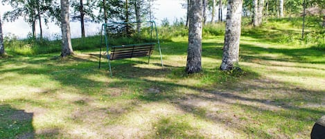Un parco con una panchina, alberi e un lago.