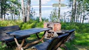 Tunnelmallinen ulkoilmalounausalue, jossa on tiiliuuni ja penkit, ja josta avautuu näkymä järvelle.