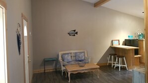A living room with a sofa, a coffee table, and a small bar area with stools. - “Cozy Mountain Suites - #5 just 5 minutes from Glacier Park (Coram)