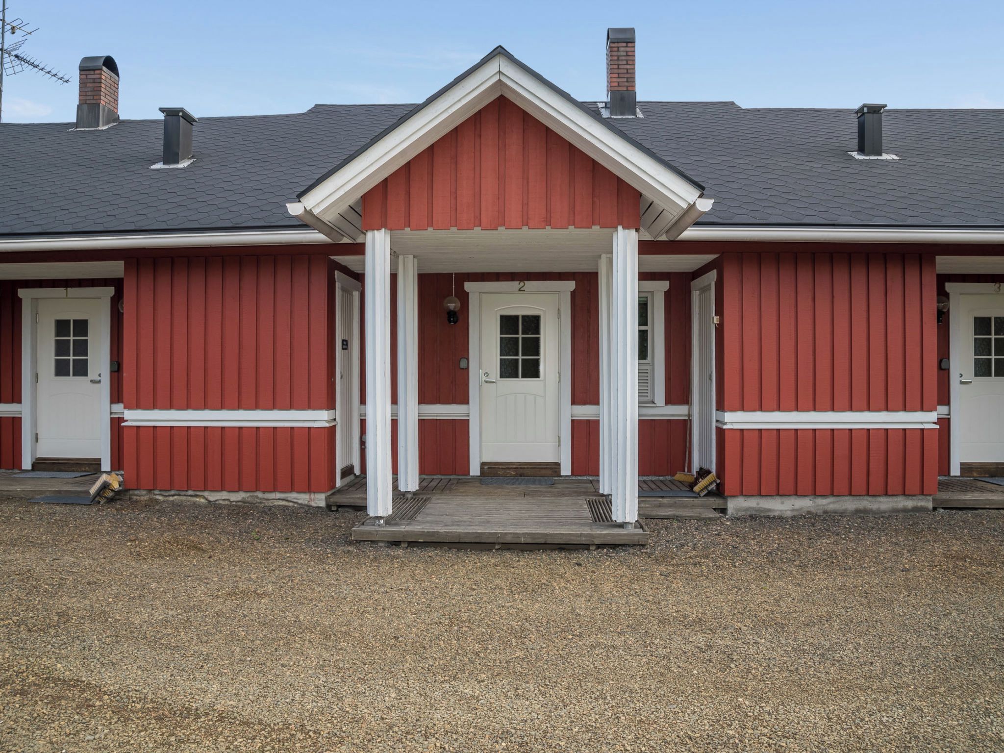 A red building with a white entrance and two chimneys.