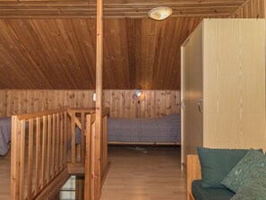 Un intérieur en bois avec un lit superposé, un petit coin salon et une armoire en bois.