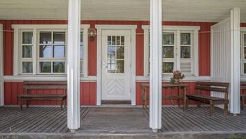 A wooden porch with benches and a door.