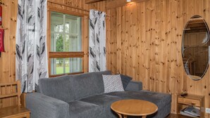 Una camera accogliente con un divano grigio, un piccolo tavolo di legno e uno specchio appeso al muro.