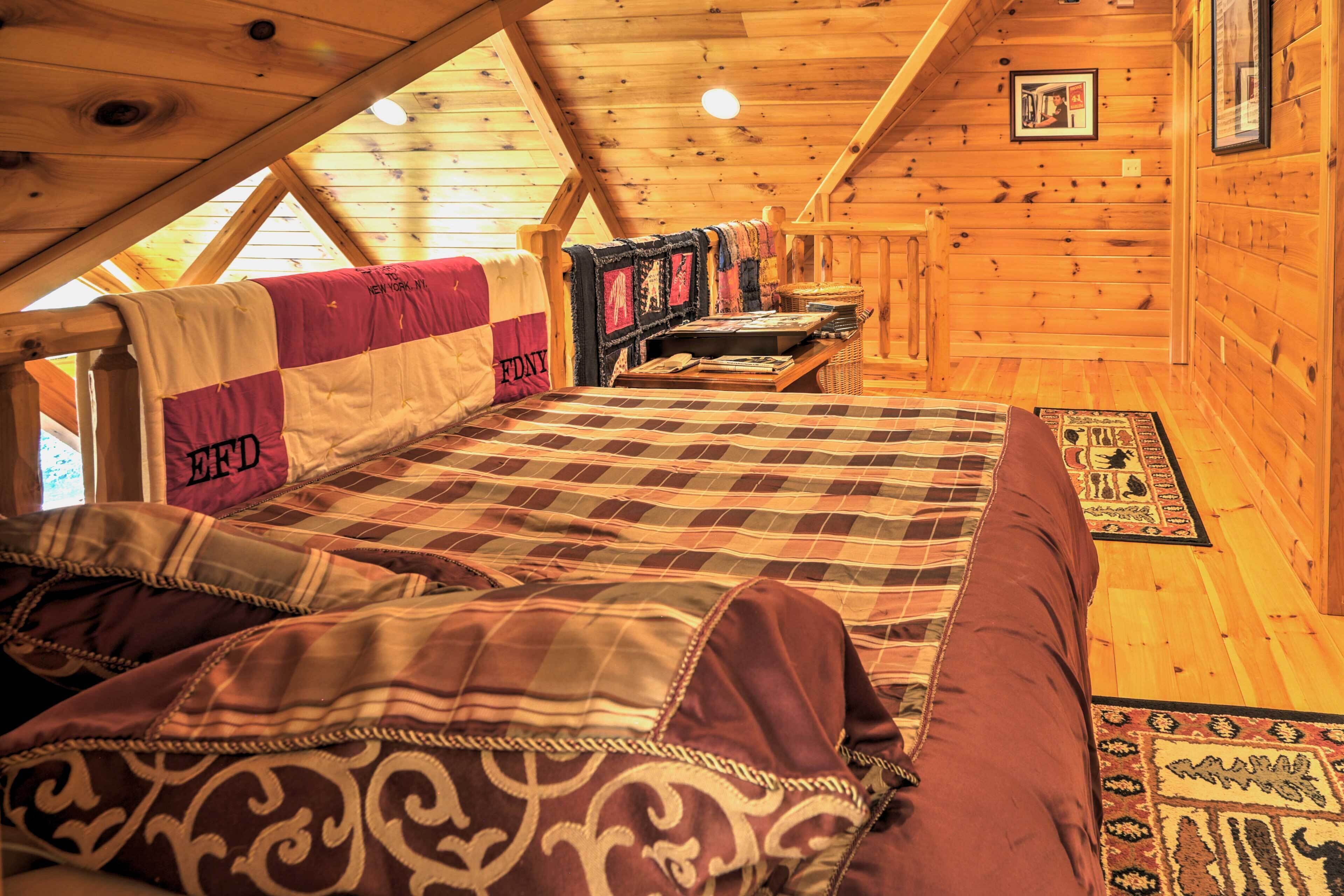 Une chambre confortable dans un chalet en rondins, avec un lit, des oreillers, une courtepointe et une petite table sur laquelle se trouve un panier.