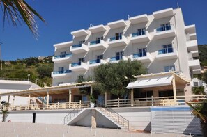 Un hotel de varios pisos con balcones, una entrada cubierta y una escalera que conduce a la recepción.