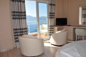 A hotel room with a balcony, a television, and a seating area with a chair and ottoman. - Hotel Coral (Vlorë)