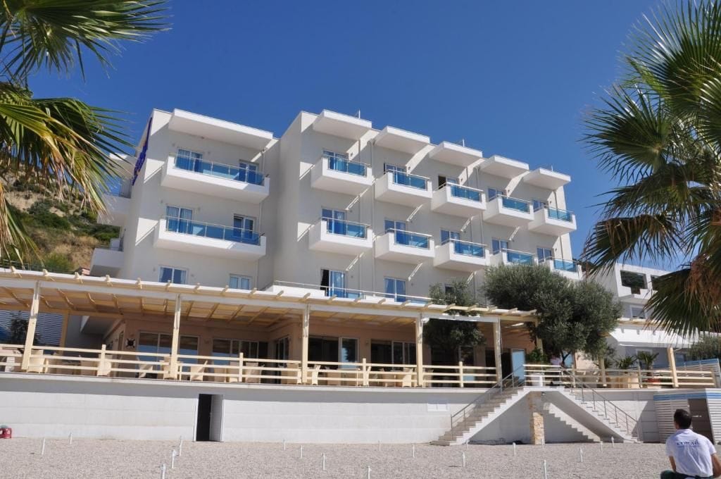 Ein mehrstöckiges Hotel mit Balkonen, einem überdachten Außenbereich und einer Treppe, die zum Eingang führt.