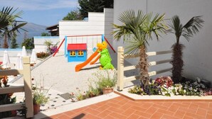 A children's play area with a slide, a small house, and palm trees. - Hotel Coral (Vlorë)
