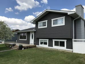 A two-story house with a dark siding exterior, white trim, and a front porch with steps.