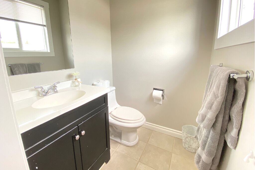 A bathroom with a sink, mirror, toilet, and towel rack.