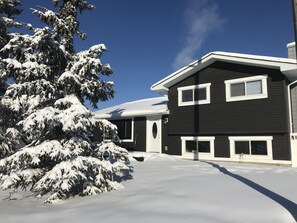 A two-story house with a snow-covered roof and driveway.