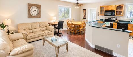 A living room with a sofa, coffee table, and a dining area with chairs.