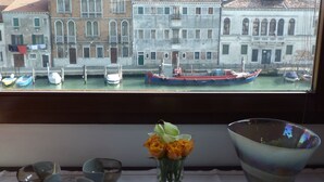 Blick aus dem Fenster auf historische Gebäude und einen Kanal mit Booten in Venedig.