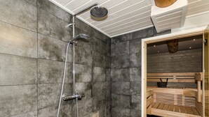 A modern bathroom with a shower, a wooden bench, and a sauna. - Savilahti by Interhome (Juuka)
