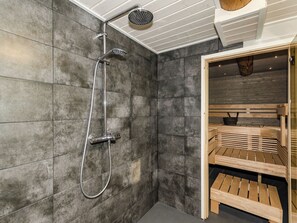 Un bagno moderno con doccia, sauna in legno e uno specchio grande.