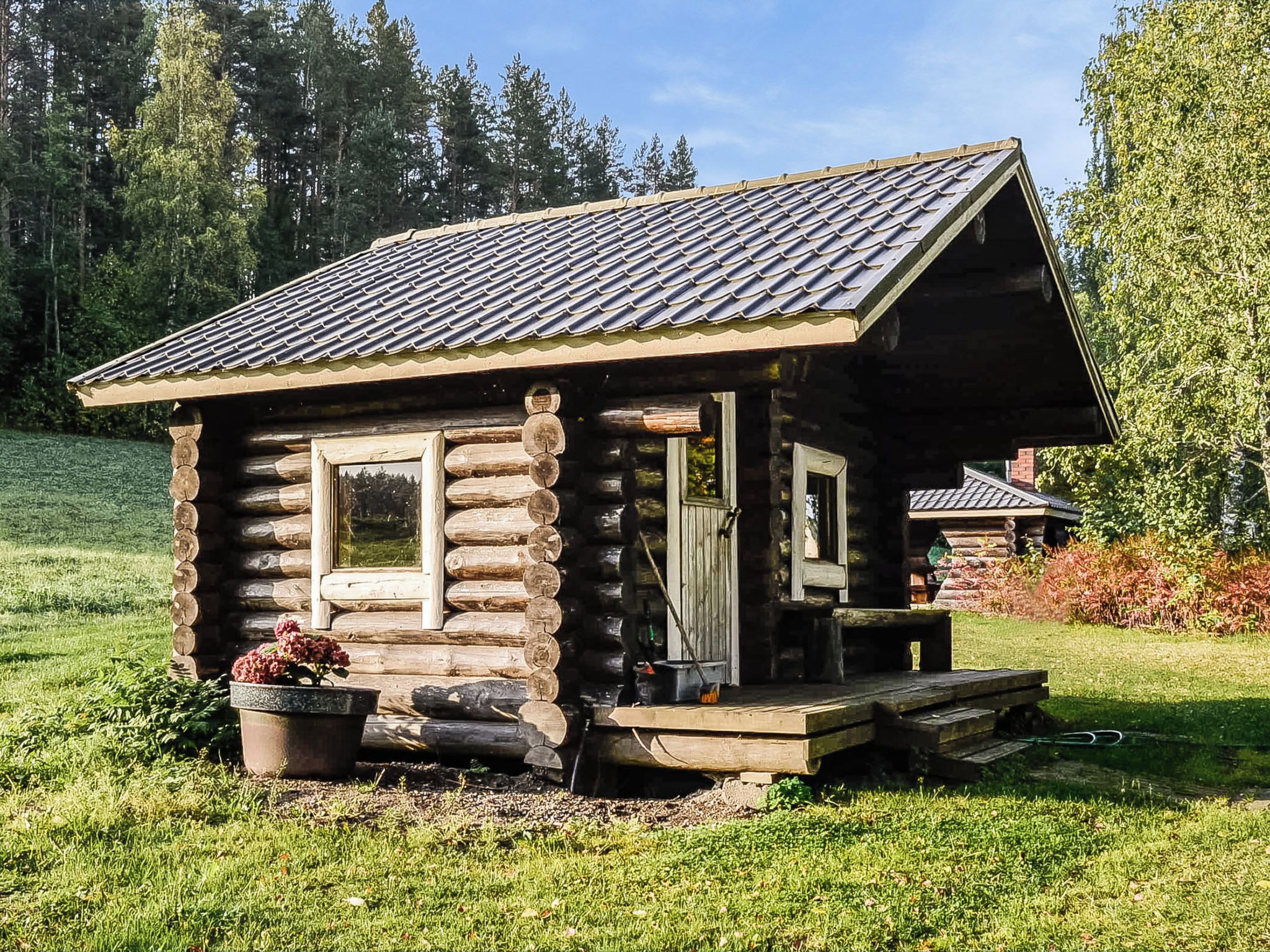 A log cabin with a pitched roof, a porch, and a window.