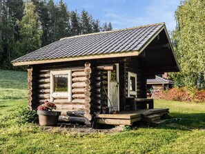 Una baita di legno con tetto a spiovente, un portico e una finestra.