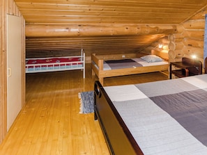 A cabin with a wooden interior, a bunk bed, a single bed, and a small table. - Savilahti by Interhome (Juuka)