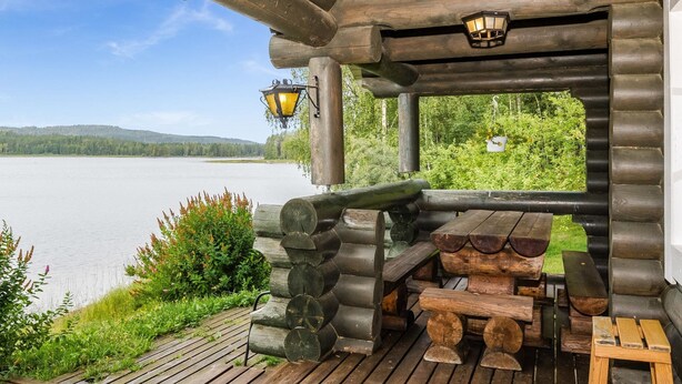 A wooden deck with a log bench and table, overlooking a lake with a forested backdrop. - Savilahti by Interhome (Juuka)