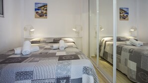 Une chambre d’hôtel avec deux lits, un grand miroir et des œuvres d’art accrochées aux murs.