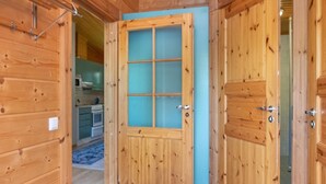 A wooden door with a glass panel, leading to a kitchen area with cabinets and appliances. - Rusakko by Interhome (Sotkamo)
