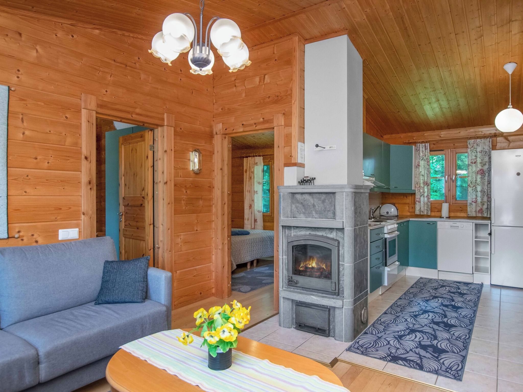 A cozy log cabin interior with a living room, a fireplace, a kitchen, and a dining area.