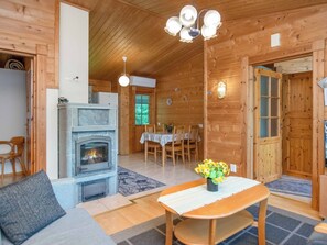 Ein gemütliches Blockhaus-Interieur mit Kamin, Essbereich und Holzbalkendecke.