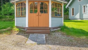 A small, single-story wooden structure with a gabled roof, a front door, and large windows. - Rusakko by Interhome (Sotkamo)