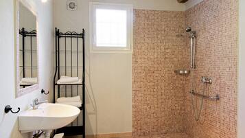 Ein Badezimmer mit Waschbecken, Spiegel, Handtuchhalter und Duschbereich mit Mosaikfliesen.