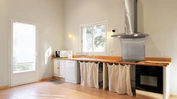 A kitchen with a stainless steel range hood, a built-in oven, and a window above the sink.