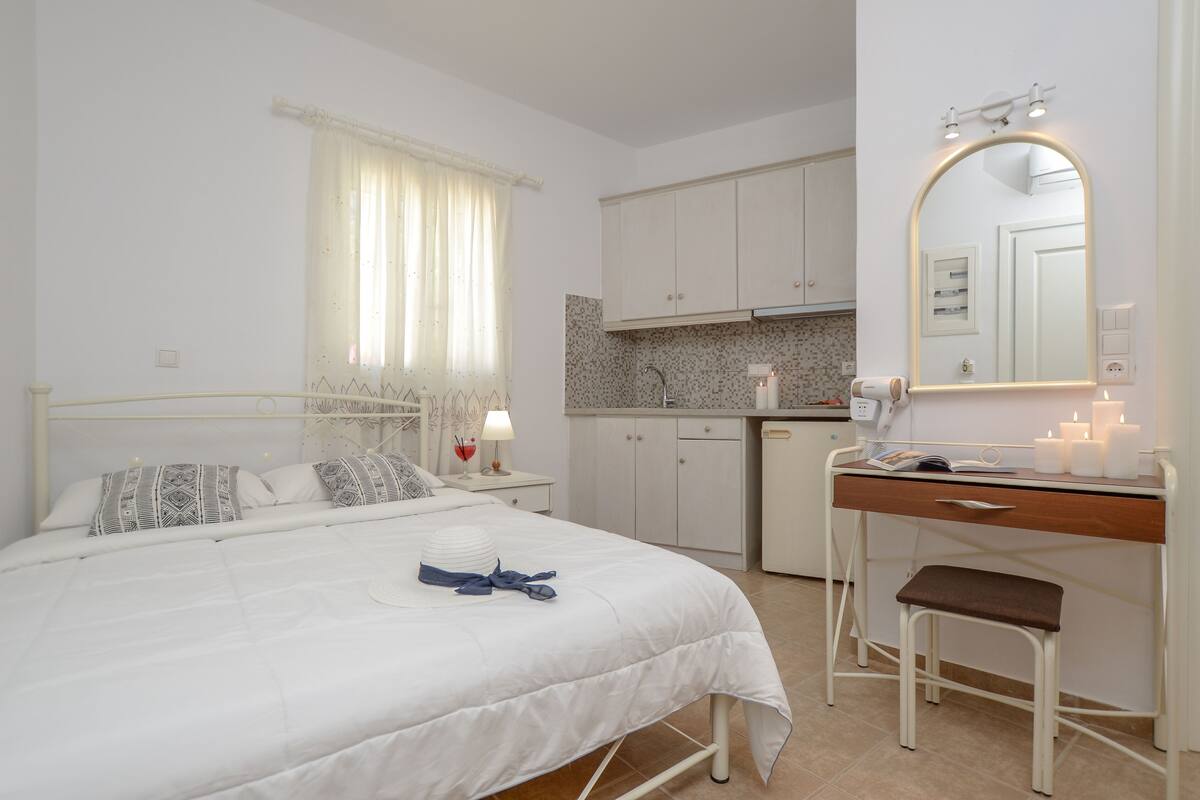 A bedroom with a bed, bedside table, and a small desk with a chair.