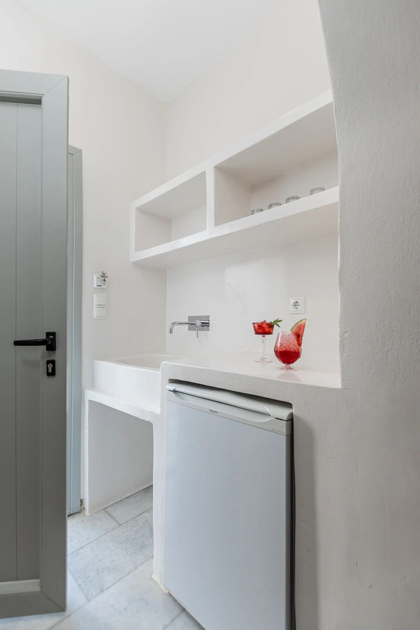 Una cocina moderna con muebles blancos, un refrigerador empotrado y una encimera con dos vasos de fruta.