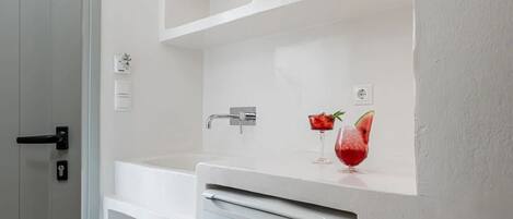 Una cocina moderna con muebles blancos, un refrigerador empotrado y una encimera con dos vasos de fruta.