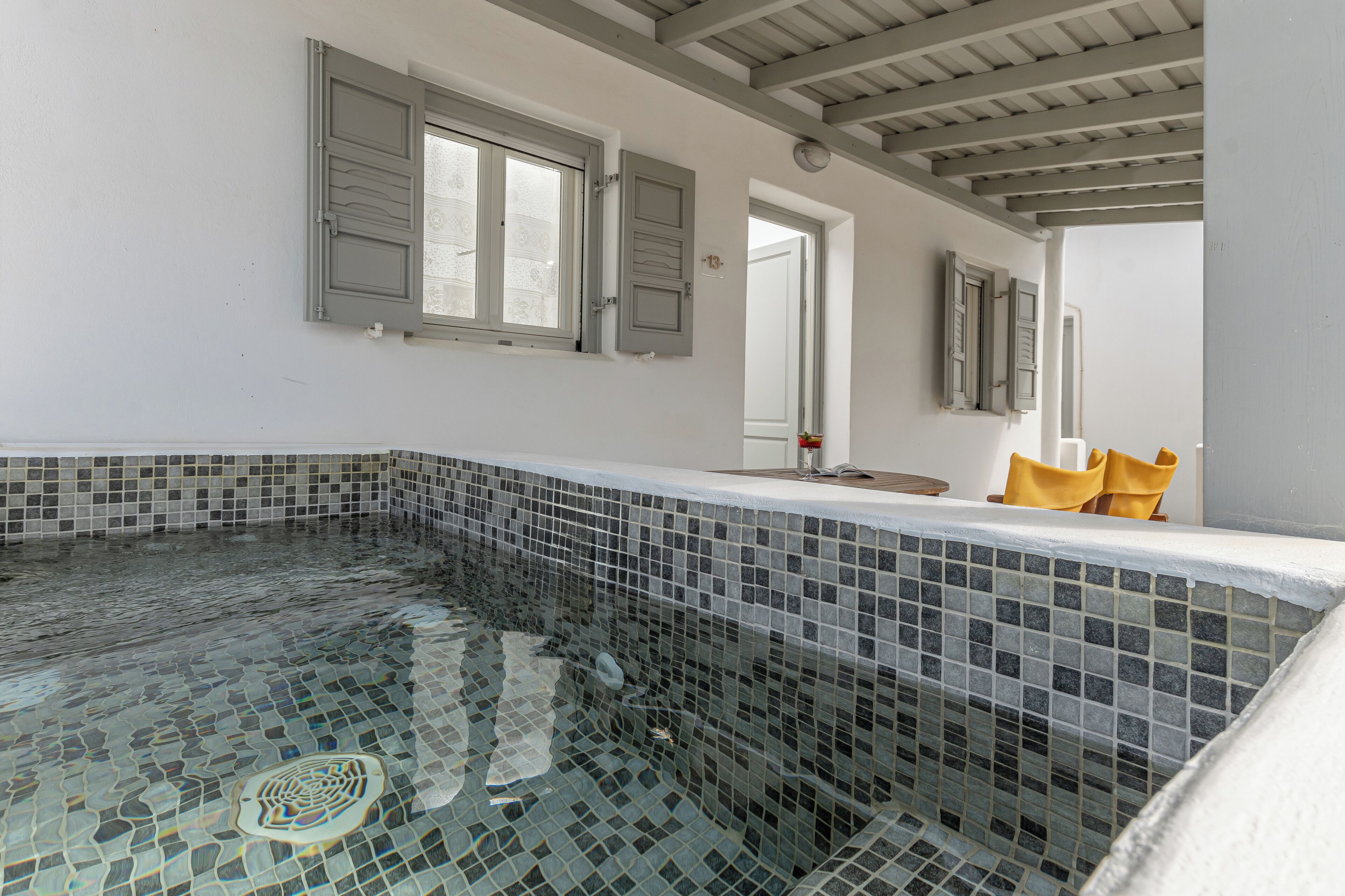 A room with a tiled swimming pool, a wooden ceiling, and a door with a window.