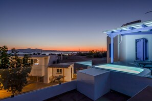 A rooftop terrace with a pool, a dining area, and a view of the sunset over the sea. - Golden Sand Naxos (Naxos)