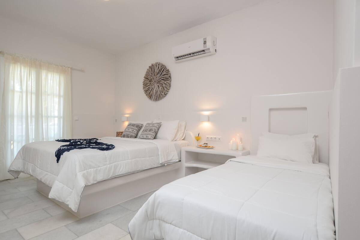 A hotel room with two beds, a wall-mounted air conditioner, and a decorative wall piece.